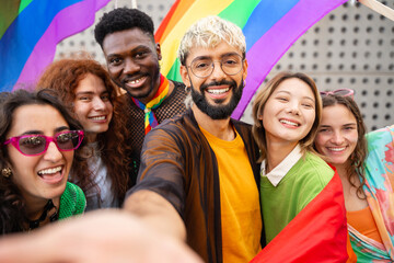 Happy friends taking a selfie photo in the city - Young diverse alternative people having fun with LGBT rainbow flags - obrazy, fototapety, plakaty