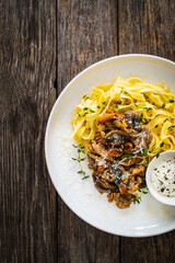 Tagliatelle with roast pork loin, parmesan cheese and mushrooms served on wooden table
