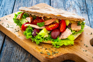 Pita with tuna greek salad on wooden table
