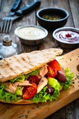 Pita with tuna greek salad on wooden table
