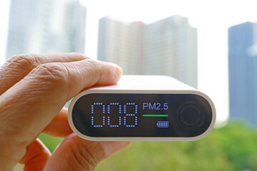 Closeup of an air quality sensor in hand with group of high buildings in the backdrop
