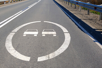 A road sign on the asphalt in front of the bridge prohibits overtaking.