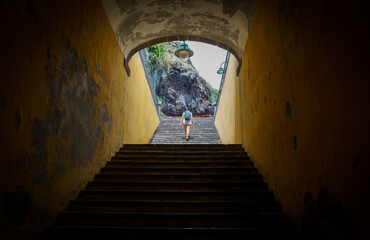 Foto de una chica subiendo unas escaleras en la isla de Madeira con paredes amarillas y roca volcánica al fondo.