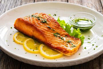 Seared salmon steak with lettuce and lemon on wooden table
