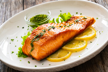 Seared salmon steak with lettuce and lemon on wooden table
