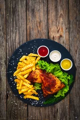 Poster Roasted chicken thigh with French fries, lettuce and tomato on wooden table  © Jacek Chabraszewski
