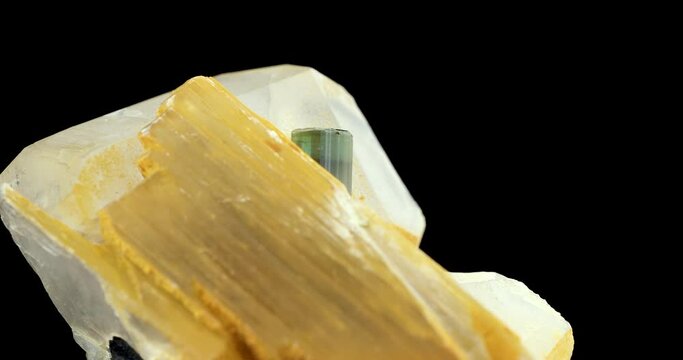 Elbaite verdelite (green tourmaline), on quartz and muscovite rotating in 4k isolated on black background. macro detail close-up rough raw unpolished semi-precious gemstone. 