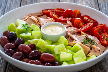 Tuna greek salad on wooden background
