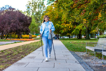 Nordic walking - mid-adult woman exercising in city park
 - obrazy, fototapety, plakaty