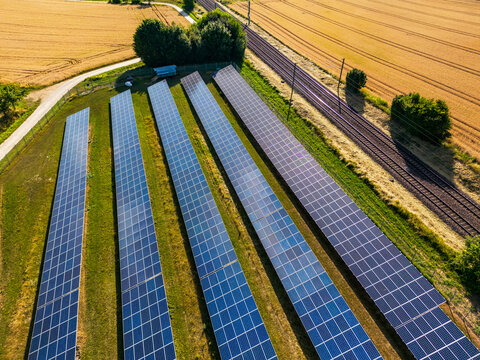 Solarfeld mit Solarmodulen auf dem Land neben einer Bahntrasse
