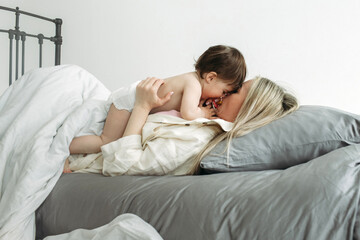 A mother and her little daughter are lying in bed, they woke up and the child threw out the...