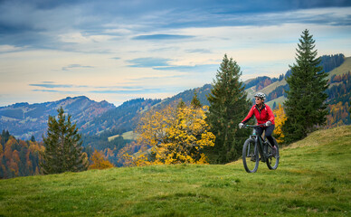 pretty senior woman riding her electric mountain bike in autumn and enjoying the spectacular view...