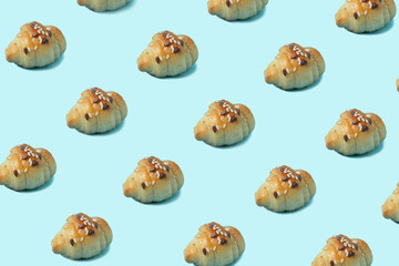 Pattern make of rolls kifla on bright blue background. Creative food background.