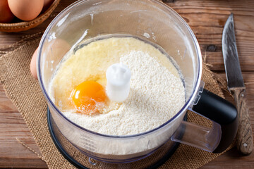 From above blender bowl with flour and egg on a table