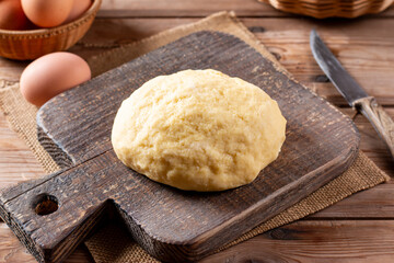 Raw dough on a cutting board on a wooden table. Making pastry.