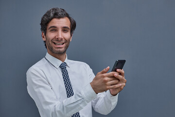 young successful man on a gray background typing on the phone