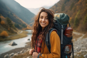 Smiling female tourist holding backpack and traveling in the mountains