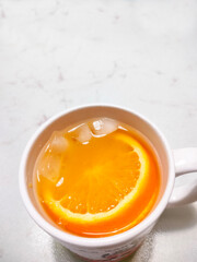 fruit punch in a mug served with sliced orange and ice cubes with white background. Top view. Negative space