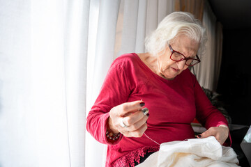 A grandmother sewing on her sofa at home