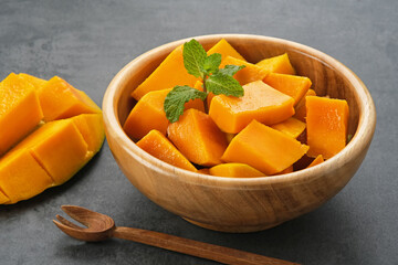 Fresh and ripe mango fruit slice on wooden bowl
