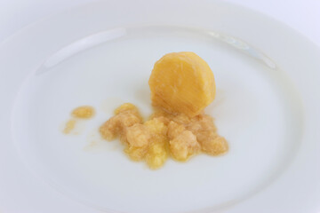 A miniature grater and grated potatoes on a white plate.
