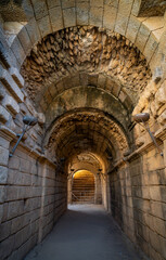 Interior of one of the entrances to the stands and stage of the ancient Roman Theater of Mérida, with a vaulted ceiling of stones and rocks and torches on the walls. Sunlight through the stairs.