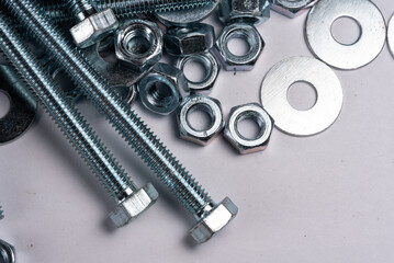 Bolts, nuts and washers in close-up scattered on a white background. Background with metal elements.