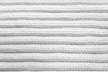 White knitted background. Texture of knitted woolen fabric with horizontal lines. Scarf or sweater close-up.