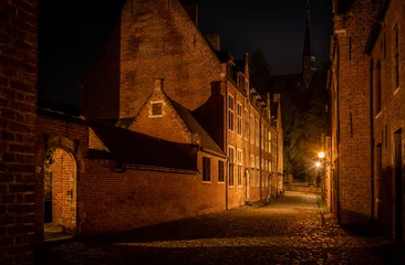 Deurstickers residential student houses in the Groot Begijnhof historic district of Leuven at night with streetlamp light. Atmospheric street photography showing old stone roads with pretty red brick buildings © drew