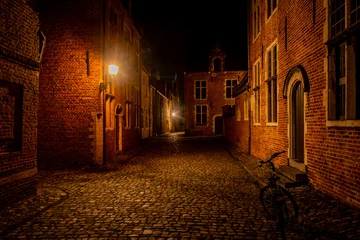 Deurstickers residential student houses in the Groot Begijnhof historic district of Leuven at night with streetlamp light. Atmospheric street photography showing old stone roads with pretty red brick buildings © drew