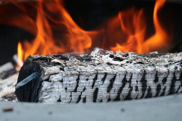 charred log burning with flames visible