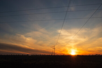 Power line against the backdrop of a landscape with a sunset, electric poles, evening, steppe Ukraine