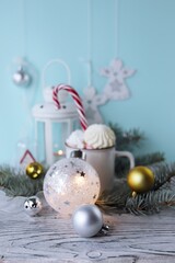Christmas decorations, a cup of coffee with meringues and marshmallows, a lantern with a burning candle, glowing balls and New Year's toys on a background with fir branches