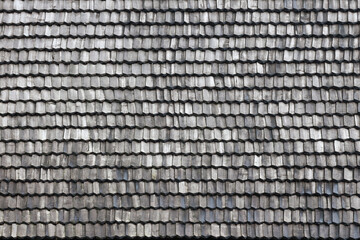 Gray wooden roof tiles background texture. A close up of old gray roof covered with wooden tiles or shingles