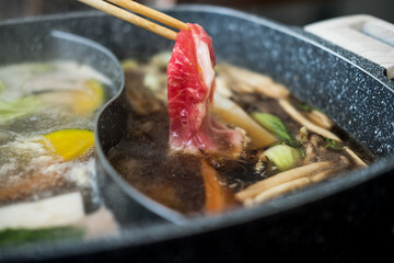 Raw beef slice on wood chopsticks for Japanese sukiyaki or hot pot. Delicious food most popular in Thailand.