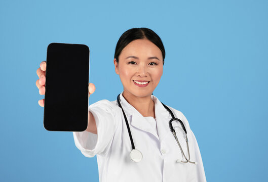 Happy Asian Doctor Woman Holding Big Blank Smartphone With Black Screen