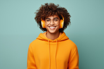 Fototapeta na wymiar Happy guy in bright yellow headphones, on solid studio background,