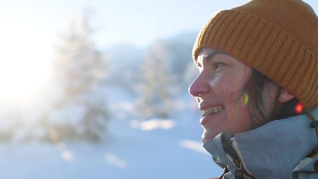 Smiling woman with braces on her teeth, beautiful smile in slow motion. portrait of a girl against the backdrop of winter mountains and snow-covered trees. winter day off.