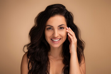 Attractive brunette long-haired young woman touching under eyes skin