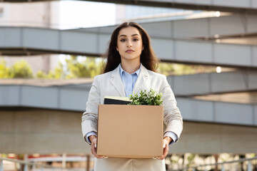 Sad serious young caucasian woman manager hold cardboard box filled with office essentials