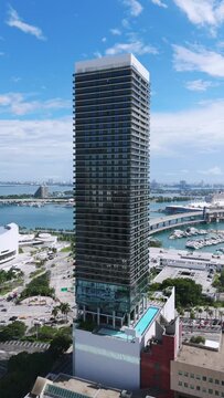 Establishing shot of impressive super-tall in Miami downtown on busy summer day. Breathtaking view of luxurious skyscraper with modern amenities on sea bay background