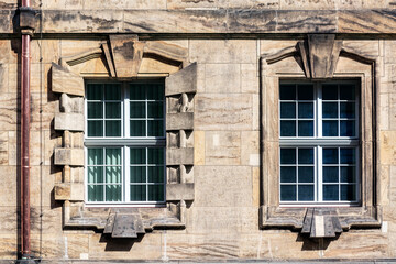 Two rectangular windows on the wall made of stone blocks and a copper downpipe. From the Windows of the world series.