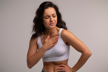 Sick millennial woman in white top suffering from heartburn