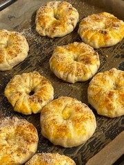 Close-up of ring-shaped pastries fresh from the oven, sprinkled with sugar and spices on parchment paper