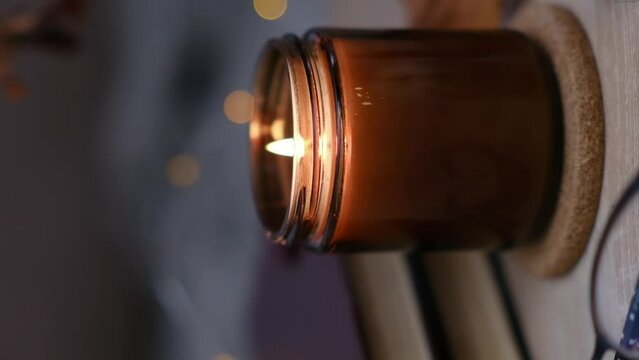 Autumn home disign: burning candle, with lights and glasses on table in cozy living room.