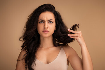 Unhappy brunette young woman showing long hair split ends