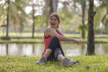 Naklejka na ściany i meble Asian young women enjoy exercising in the public park. Stretching the body and taking a breath of fresh air. The fresh air helps to feel more energized.