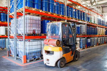 Forklift rides inside warehouse. Storage building. Logistics center with multi-tiered racks. Forklift without driver. Warehouse of factory. Fuel barrels on pallets. Forklift for warehouse center