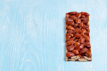 Almond bar with honey on a light blue wooden background with copy space