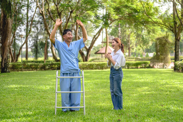 Naklejka na ściany i meble Daughter takes care of father and encourages him during his illness at hospital garden. The happiness of old adult patients while rehabilitation or physical therapy of retired patients.